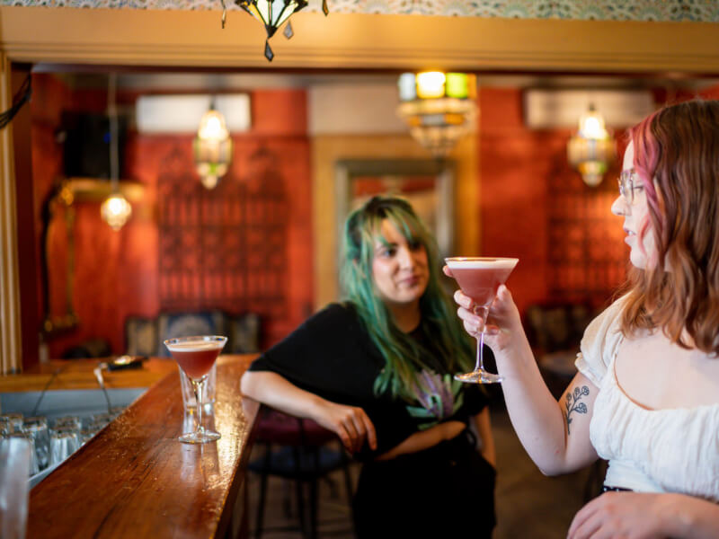 Two women chat as they sip on handmade cocktails at the bar.